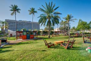 a park with chairs and a table and palm trees at InterContinental Muscat by IHG in Muscat