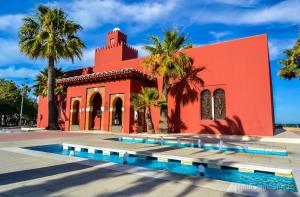 un edificio rojo con palmeras y una piscina en Pueblo del parque 12 - Terraza - Piscina y Playa- Urbanización tranquila- Perfecto para descansar, en Benalmádena
