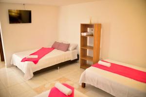 a small room with two beds and a tv at Hotel Casa Alejandria in Quimbaya