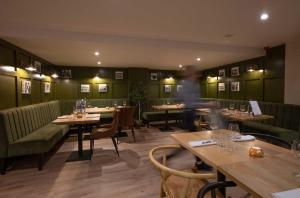 un restaurante con mesas de madera y cabinas verdes en Tregarthen's Hotel en Hugh Town