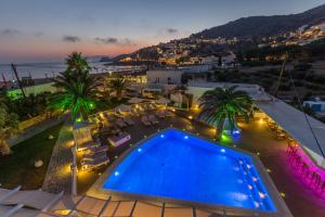 uma vista para uma piscina e para o oceano à noite em Hotel Aegeon em Mylopotas