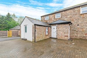 a brick house with a white door and a driveway at Coniston House, 3 bedrooms with parking, Appleby by Guestz in Kirkby Thore