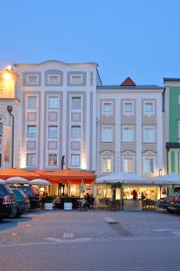 un grande edificio con tavoli e ombrelloni in un parcheggio di Appartement-Hotel GH Zum Goldenen Schiff a Enns