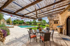 un patio con mesa, sillas y piscina en YourHouse Son Costa Villa, en Sineu