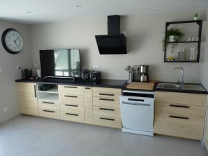 a kitchen with wooden cabinets and a sink and a clock at Sol-y-Days Darse, Superbe appartement de type Marina avec belle terrasse vue port de plaisance in Le Grau-du-Roi