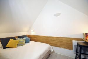 - une chambre dotée d'un lit blanc avec des oreillers jaunes et bleus dans l'établissement ULVF les Ramondies, à Saint-Lary-Soulan