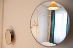 ein Spiegel, der ein Zimmer mit einem Fenster reflektiert in der Unterkunft GREEN APPART2 La Doller avec Jardin Privé in Mulhouse
