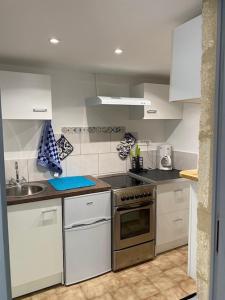 a kitchen with white cabinets and a stainless steel oven at Charmant studio à 2 pas du centre historique in Sommières