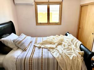 ein unmaskiertes Bett in einem Zimmer mit Fenster in der Unterkunft Cheerful, sun-kissed room with workstation in Revere