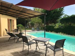 a patio with chairs and an umbrella next to a pool at Les Mas du Peintre in Sarlat-la-Canéda