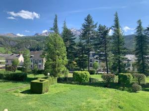 einen Hof mit Bäumen, Häusern und Bergen im Hintergrund in der Unterkunft Studio les mélèzes vue montagne in Barcelonnette