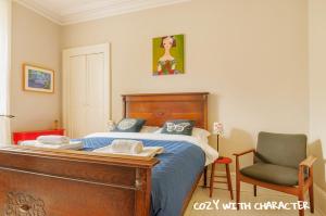 - une chambre avec un lit en bois et une chaise dans l'établissement Cozy with Character Vibrant Cottage Style Flat at Leith Links Park, à Édimbourg