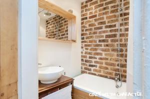 een badkamer met een wastafel en een bakstenen muur bij Cozy with Character Vibrant Cottage Style Flat at Leith Links Park in Edinburgh