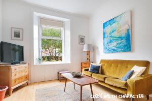 a living room with a couch and a tv at Cozy with Character Vibrant Cottage Style Flat at Leith Links Park in Edinburgh