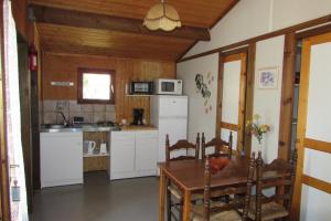 a kitchen with a table and a white refrigerator at Les chalets du Verger des Ascarines in Corneilla-de-Conflent