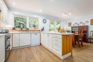 a large kitchen with white cabinets and a dining room at 3 bedroom bungalow with htub & private loch access in Crieff