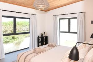 a bedroom with a bed and large windows at Vila Luxo da Praia in Casal da Lagoa Seca +74 photos
