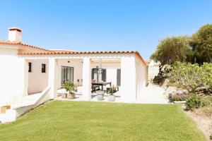a white house with a lawn in front of it at Vila Luxo da Praia in Casal da Lagoa Seca