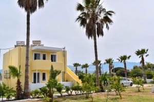 a yellow house with palm trees in front of it at LambiSea Apartment 2 in Kos Town