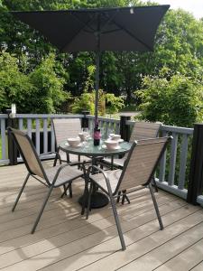 a table and chairs with an umbrella on a deck at No1 Borwick Lakes in Carnforth