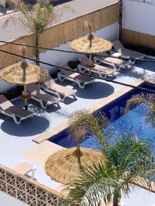 卡拉納雅達的住宿－Hotel Chevy & Suites，一组椅子和遮阳伞,位于游泳池旁