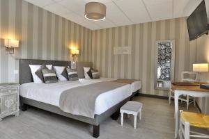 La CoquilleにあるLogis Hôtel-Restaurant Les Voyageursの大きなベッドとデスクが備わるホテルルームです。