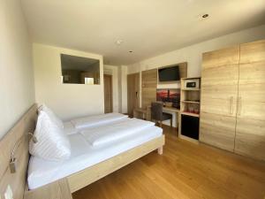 a bedroom with a large white bed and a desk at Seehotel Herlinde in Podersdorf am See