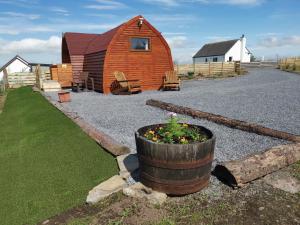 a barn and a barrel with flowers in front of it at Achmeney Glamping Pod Larger than Average Pod in Halkirk