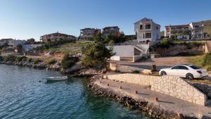 a white car parked next to a river with houses at Apartments Suzy in Šibenik