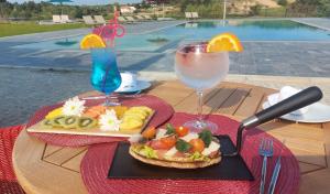 a table with a plate of food and two drinks at Grapple Hotel & Spa in Carrazeda de Anciães