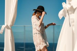 une femme portant une robe de dentelle blanche et un chapeau noir dans l'établissement Hyatt Regency Malta, à San Ġiljan