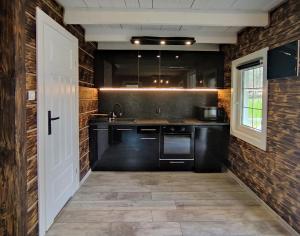 a kitchen with black appliances and a brick wall at Domek pod Karpaczem in Miłków