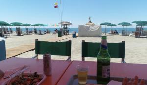 a table with a bottle of beer and a plate of food on the beach at Casa Casella, delizioso bilocale a due passi dal mare in Lido di Ostia