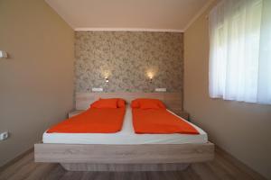 a bedroom with a bed with orange sheets and a window at Tavi Panzió in Dunapataj
