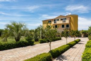 a yellow house with a brick driveway and trees at B&B Villa Oasa 2 in Rovinj