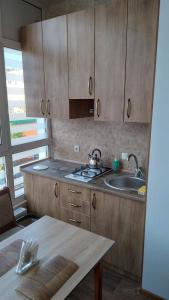 a kitchen with wooden cabinets and a sink and a table at Новобудова Центр Либiдь Плаза in Khmelʼnytsʼkyy +15 photos