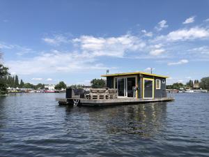 a small house on a dock on a body of water at Großes gemütliches Hausboot in Berlin in Berlin