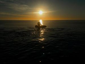 a person sitting in the water at sunset at Atlanticview Cape Town Boutique Hotel in Cape Town