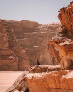a woman sitting on a rock in a canyon at Bedouin desert camp in Wadi Rum