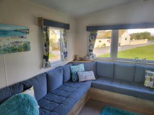 a blue couch in a living room with a window at Blackmoor Farm - Caravan 6 in Pembrokeshire