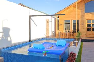 a swimming pool with blue cushions and a house at أكواخ الردسي in Al Kura