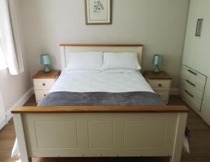 Brownstead Cottage في نافان: غرفة نوم بسرير ابيض مع مواقف ليلتين