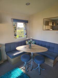 a dining room with a table and blue chairs at Blackmoor Farm - Caravan 6 in Pembrokeshire