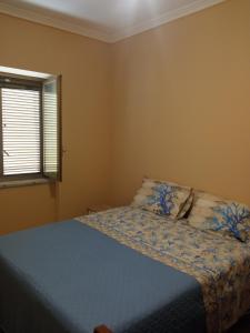 een slaapkamer met een bed met een blauw dekbed en een raam bij B&B Fronte mare in Belmonte Calabro