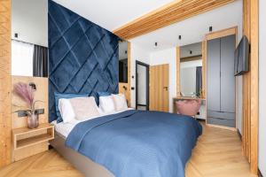 a bedroom with a large bed with a blue headboard at Wrota Chałubińskiego in Zakopane