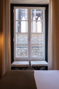 a bedroom with a window with two chairs in front at Tempo FLH Hotels Lisboa in Lisbon