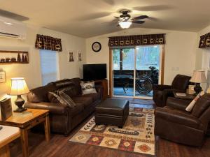 a living room with leather couches and a tv at 2 Bedroom Cabin Inside Glacier National Park in West Glacier