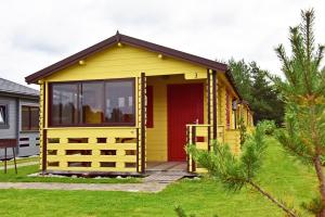 una casita amarilla con una puerta roja en Poilsio nameliai Gulbes takas, en Šventoji