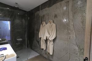 a bathroom with robes hanging on a wall at Hôtel confidentiel Le Grecale in Pianottoli-Caldarello