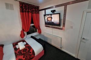 um pequeno quarto com uma cama e uma televisão na parede em *A!S* Setup for your most amazing relaxed stay + Free Parking + Free Fast WiFi * em Headingley